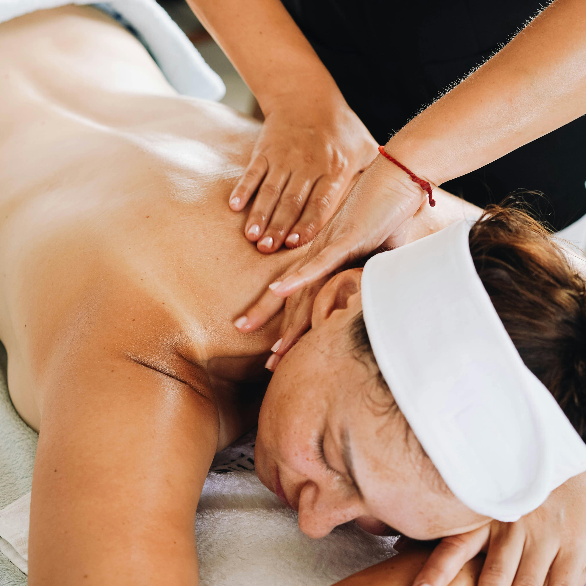 Une personne allongée face contre terre recevant un massage du dos DAHA dans un spa.