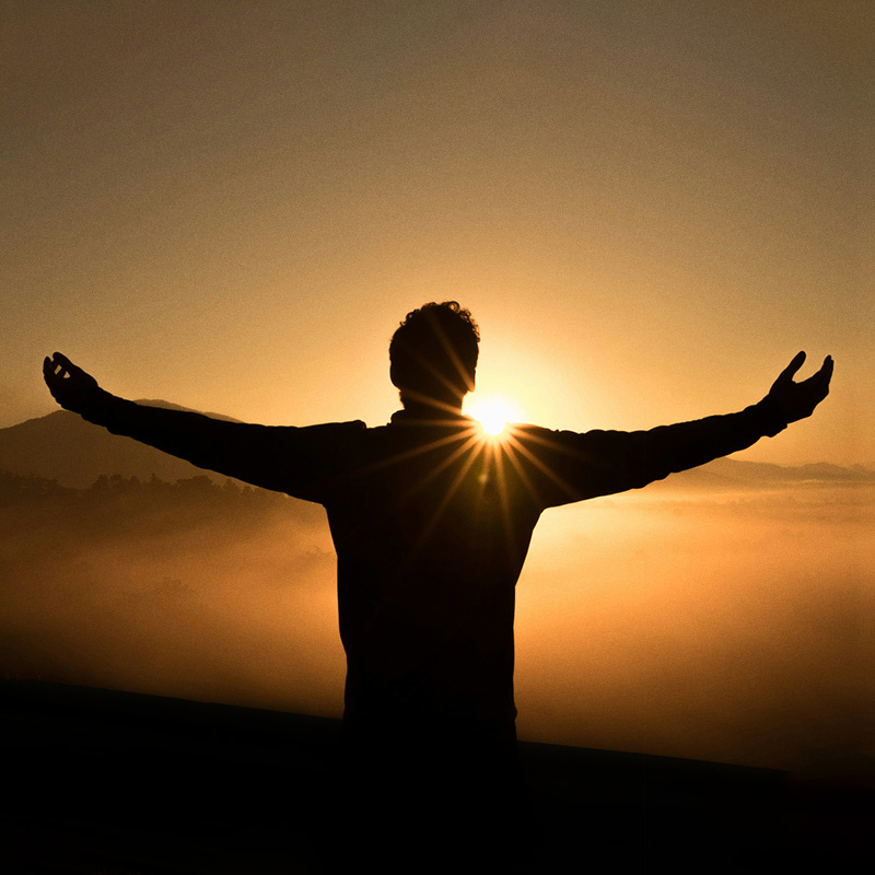 Silhouette d’une personne face au lever de soleil, symbolisant l’apaisement et le mieux-être mental.