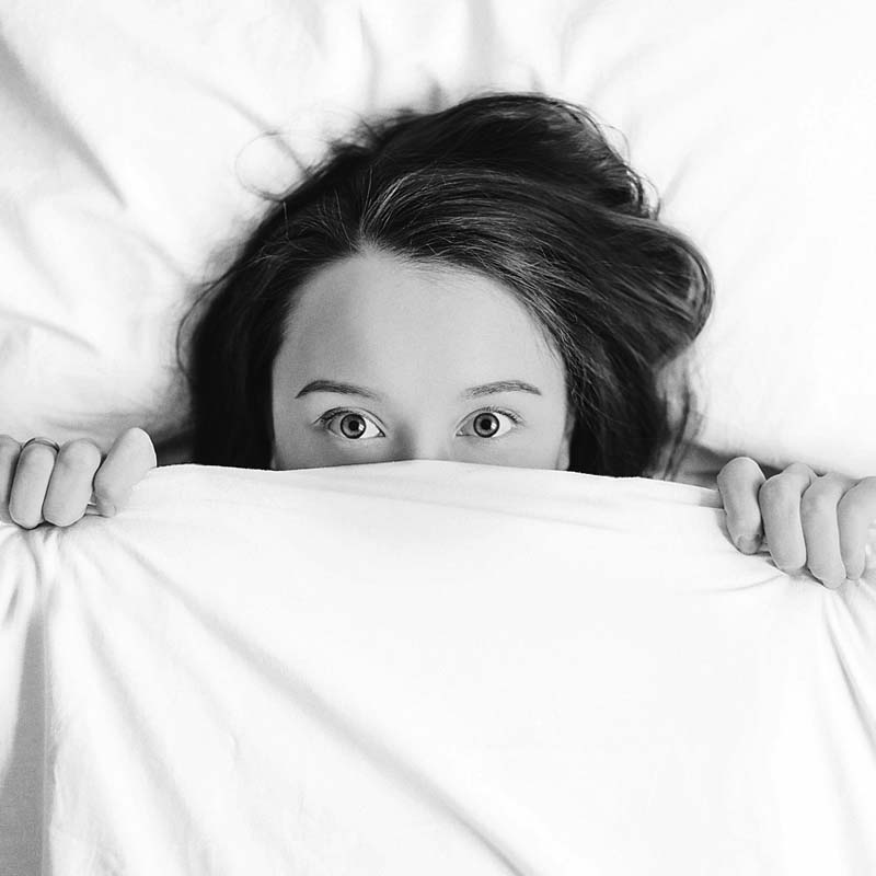 Femme cachant son visage sous un drap exprimant la peur et l'anxiété apaisées par le shiatsu
